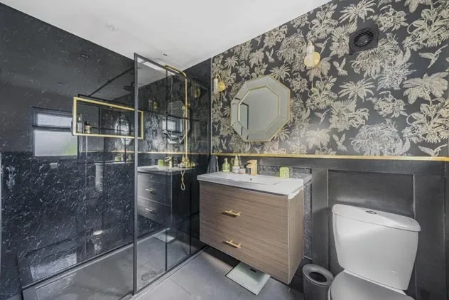 Bathroom with patterned walls, glass shower enclosure and wood vanity